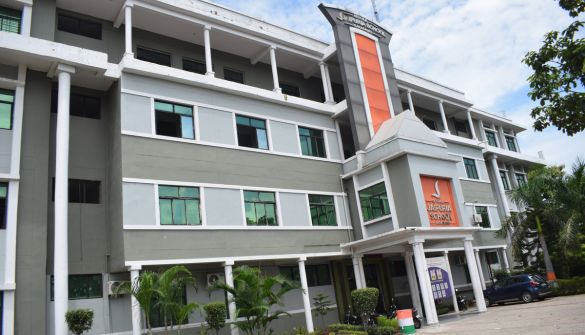 Seth M R Jaipuria School Barabanki - Jaipuria Schools - Jaipuria Schools Three-story hospital building with a gray-white facade, orange vertical sign at the entrance, and a car parked outside.
