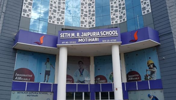 Seth M R Jaipuria School Motihari - Jaipuria Schools - Jaipuria Schools Front entrance of Seth M.R. Jaipuria School, Motihari, with a blue-purple facade, white columns, and banners featuring students.