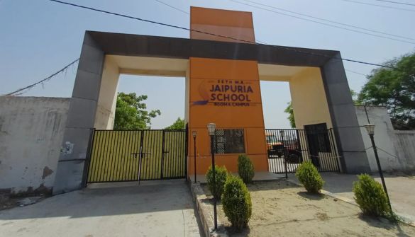 Entrance to Jaipuria School with orange central pillar and black gates, sign reading 'Jaipuria School' visible.