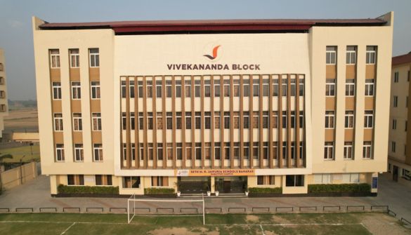 Seth M R Jaipuria Schools Banaras Babatpur Campus - Jaipuria Schools - Jaipuria Schools Aerial view of a large beige institutional building labeled 'Vivekananda Block' with many vertical windows and a manicured lawn in front.