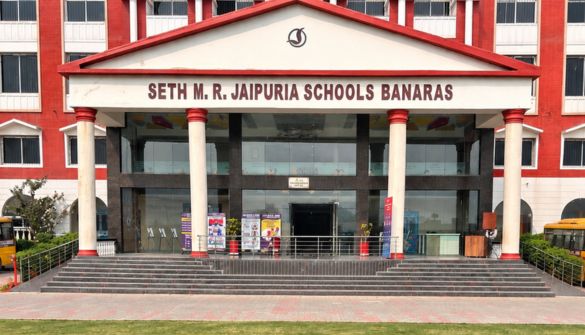 Front entrance of Seth M. R. Jaipuria Schools Banaras, a red-and-white campus with stairs and tall columns.